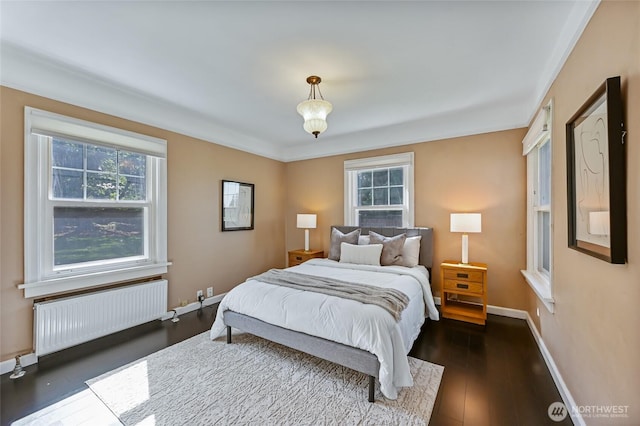 bedroom with radiator heating unit, dark wood-style floors, and baseboards