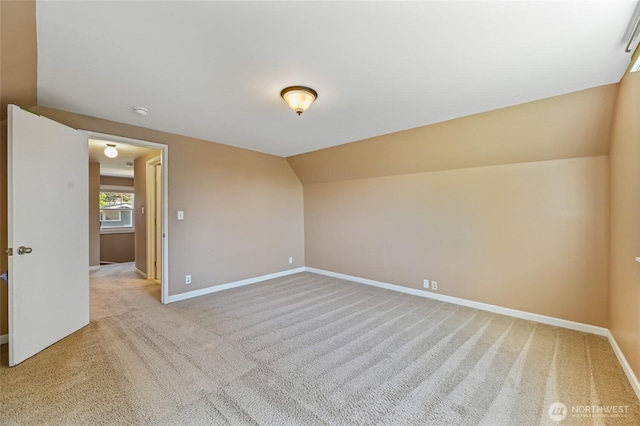 unfurnished room featuring light carpet, baseboards, and lofted ceiling
