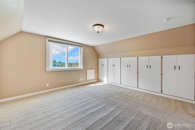 bonus room with lofted ceiling, baseboards, and light colored carpet