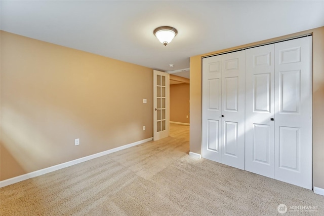 unfurnished bedroom featuring baseboards, carpet, and a closet