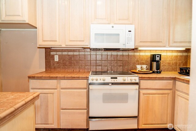 kitchen with white appliances, tile counters, and decorative backsplash