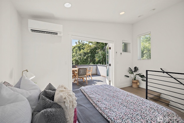 bedroom with a wall unit AC, access to exterior, wood finished floors, recessed lighting, and baseboards