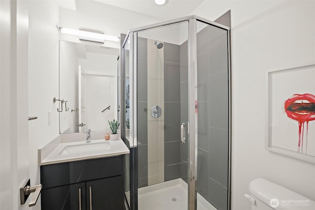 bathroom featuring a shower stall, toilet, and vanity