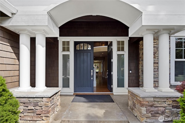 doorway to property featuring a porch and stone siding