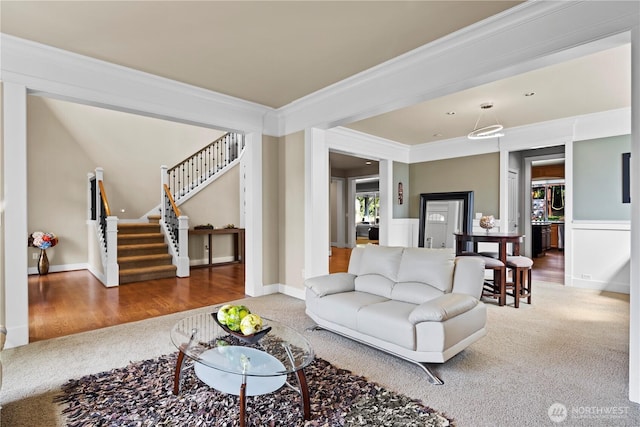 living room featuring stairs, crown molding, carpet, and wood finished floors