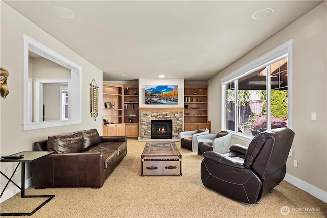 living area with baseboards, a stone fireplace, and carpet floors