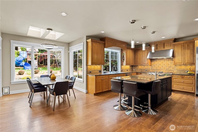 kitchen with under cabinet range hood, decorative backsplash, baseboards, and recessed lighting