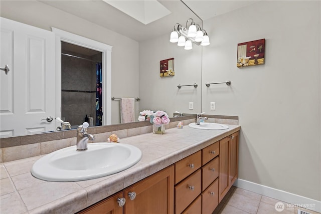 bathroom with a sink, double vanity, a skylight, and tile patterned floors