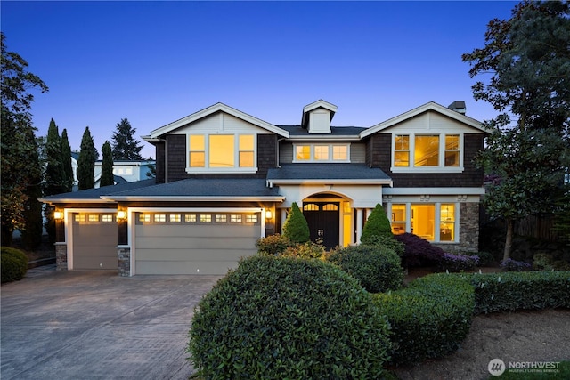 view of front of home featuring concrete driveway, a garage, and stone siding