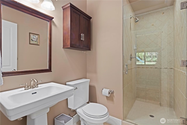 full bathroom with a stall shower, toilet, a sink, and baseboards