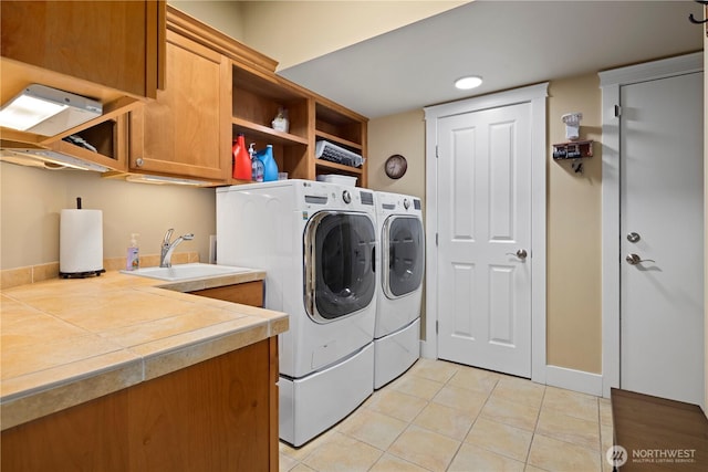 laundry area with cabinet space, washing machine and dryer, light tile patterned floors, and a sink