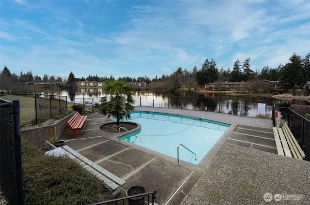 view of swimming pool featuring fence, a water view, and a patio area