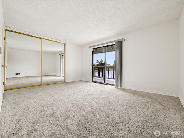 unfurnished bedroom with access to exterior, carpet floors, a textured ceiling, a closet, and baseboards