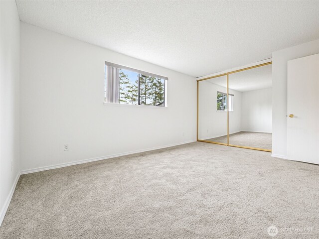 unfurnished bedroom with carpet, a closet, a textured ceiling, and baseboards
