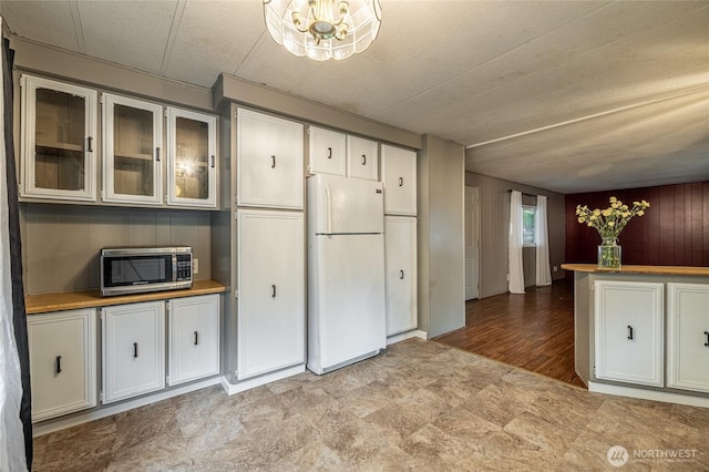 211 Pace Dr Unit 16, East Wenatchee, WA 98802 - kitchen with freestanding refrigerator, stainless steel microwave, white cabinetry, glass insert cabinets, and a chandelier