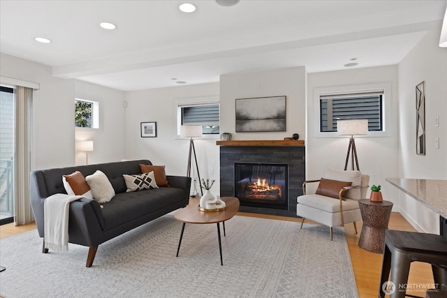 living area featuring light wood finished floors, a fireplace with flush hearth, and recessed lighting