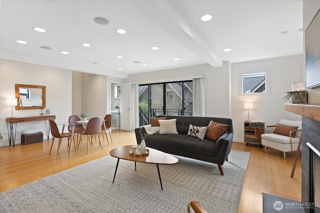 living room featuring light wood-type flooring, a fireplace, recessed lighting, beam ceiling, and baseboards