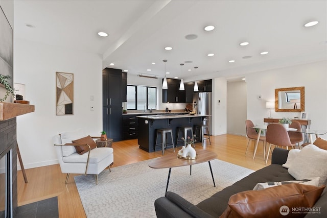 living area featuring light wood-style floors, a glass covered fireplace, recessed lighting, and baseboards