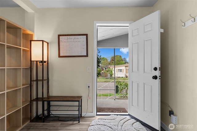 doorway to outside with lofted ceiling, wood finished floors, and baseboards