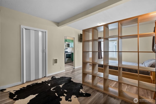 unfurnished room with baseboards, light wood-style flooring, and beamed ceiling