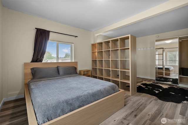 bedroom with wood finished floors, baseboards, and beam ceiling