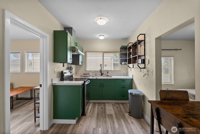 kitchen with green cabinets, stainless steel electric range oven, exhaust hood, a sink, and light wood-style floors