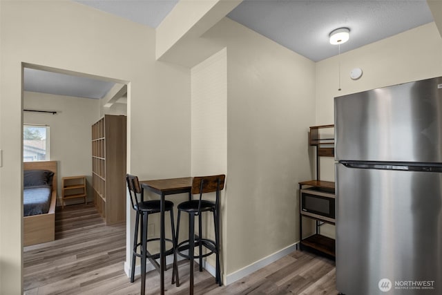 kitchen featuring appliances with stainless steel finishes, wood finished floors, and baseboards
