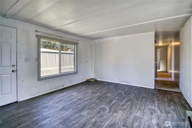 unfurnished room with dark wood-style floors and a textured ceiling