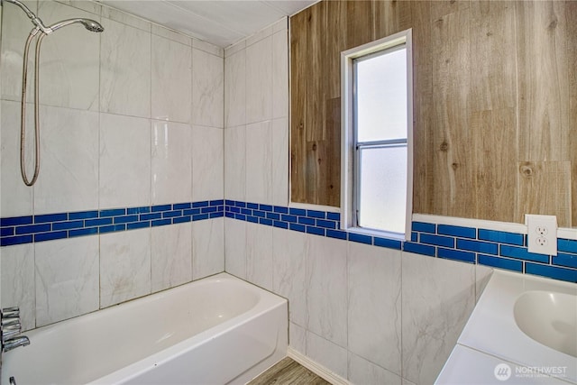 bathroom featuring tile walls, a bath, and a sink
