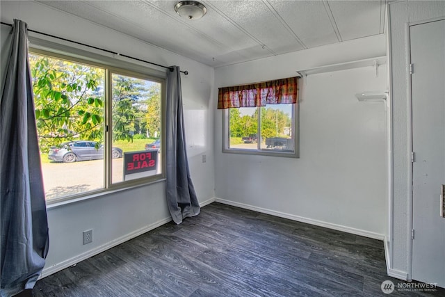 spare room featuring dark wood-style floors, baseboards, and a textured ceiling