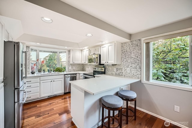 1851 58th St NE, Tacoma, WA 98422 - kitchen with stainless steel appliances, a peninsula, a sink, backsplash, and white cabinetry