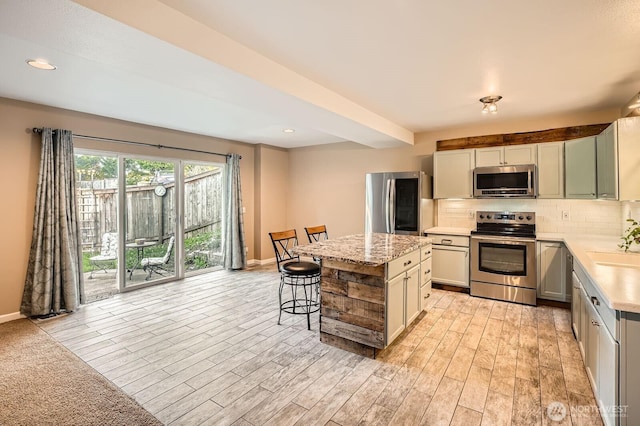 1851 58th St NE, Tacoma, WA 98422 - kitchen with stainless steel appliances, tasteful backsplash, a kitchen island, baseboards, and a breakfast bar area