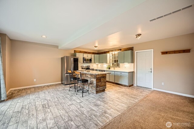 1851 58th St NE, Tacoma, WA 98422 - kitchen featuring stainless steel appliances, a kitchen bar, light wood-type flooring, and baseboards