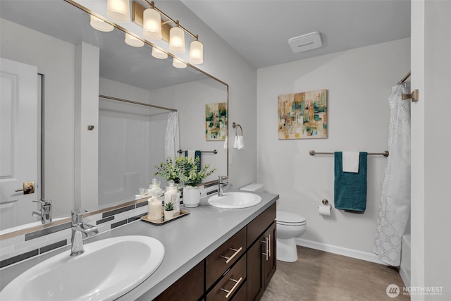 bathroom with toilet, baseboards, and double vanity