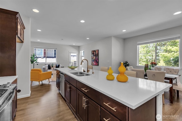 kitchen featuring a sink, open floor plan, recessed lighting, stainless steel appliances, and light countertops