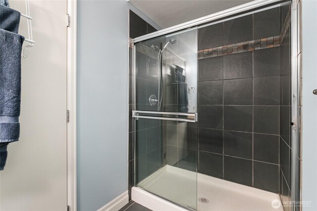 full bathroom featuring a shower stall and baseboards