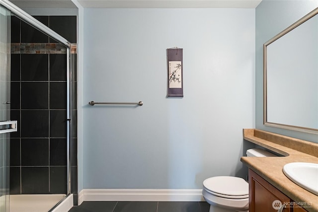 bathroom featuring a stall shower, baseboards, vanity, tile patterned flooring, and toilet
