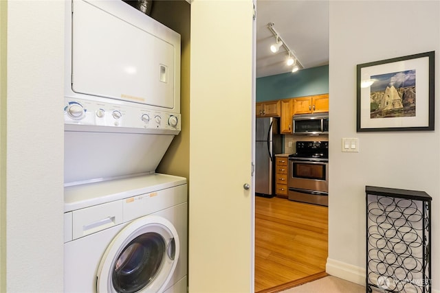 clothes washing area with stacked washer / dryer and light wood-style floors