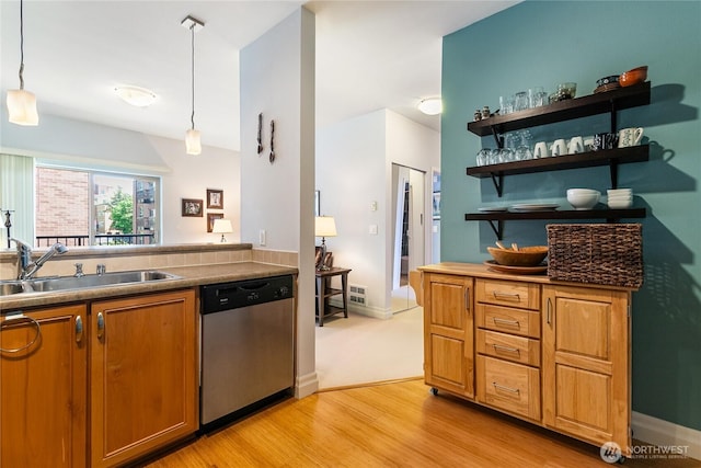 kitchen featuring stainless steel dishwasher, a sink, light wood-type flooring, brown cabinets, and decorative light fixtures