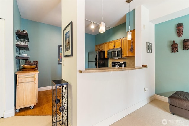 kitchen with black appliances, tasteful backsplash, baseboards, rail lighting, and decorative light fixtures