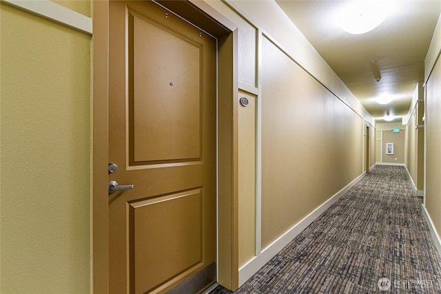 corridor with dark colored carpet and baseboards