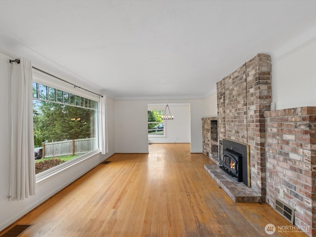 unfurnished living room featuring wood finished floors, a chandelier, and a fireplace