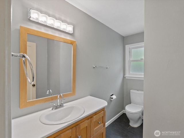 half bath featuring baseboards, toilet, and vanity