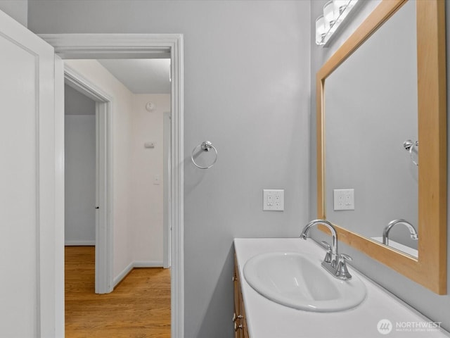 bathroom with wood finished floors, vanity, and baseboards