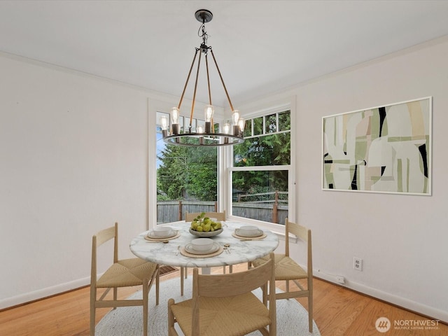 dining area featuring a chandelier, baseboards, and wood finished floors