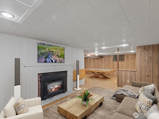 living area with wood finished floors, wooden walls, and a tiled fireplace