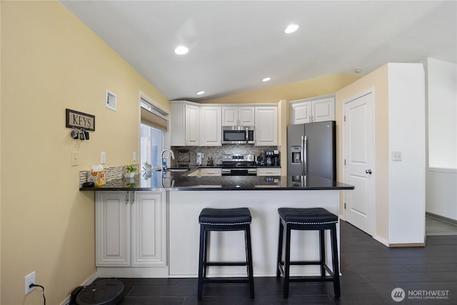 2983 Sonoran Dr, Richland, WA 99354 - kitchen featuring lofted ceiling, a peninsula, decorative backsplash, stainless steel appliances, and white cabinets