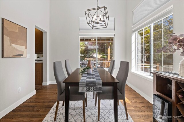 dining room featuring a chandelier, healthy amount of natural light, baseboards, and a high ceiling
