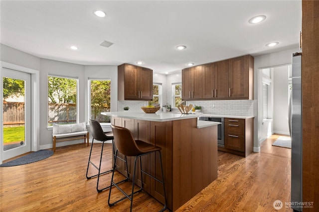 kitchen featuring a breakfast bar area, light countertops, plenty of natural light, backsplash, and recessed lighting