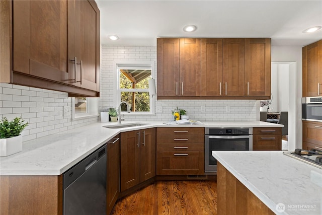 kitchen with a sink, appliances with stainless steel finishes, dark wood-style floors, backsplash, and recessed lighting